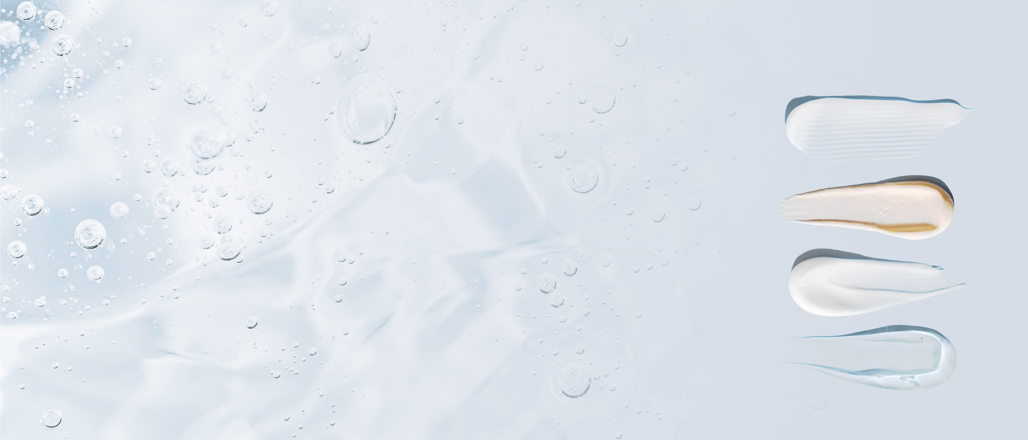 Skincare products spread on a flat surface and a background of suspended bubbles in gel