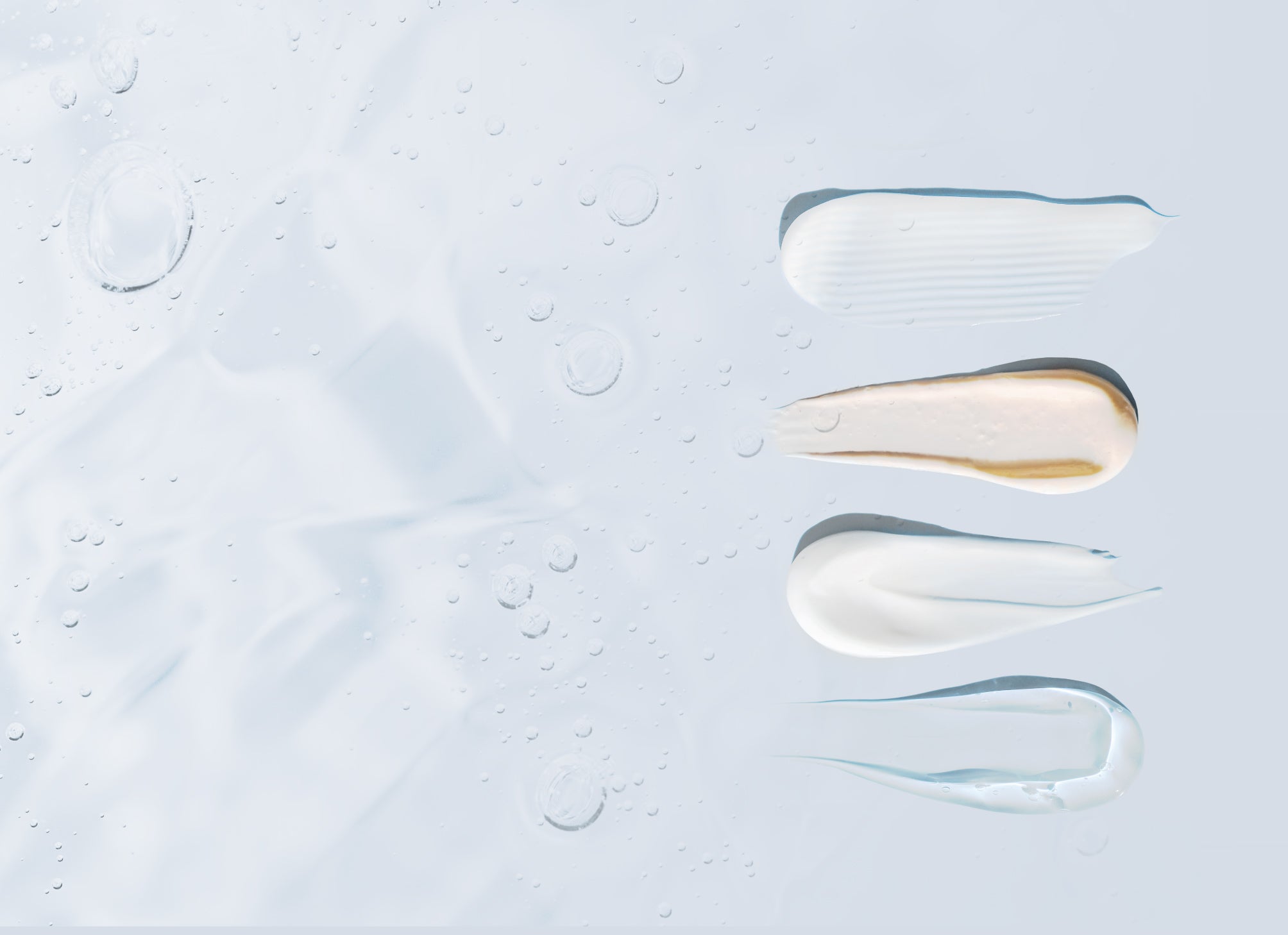 Skincare products spread on a flat surface and a background of suspended bubbles in gel